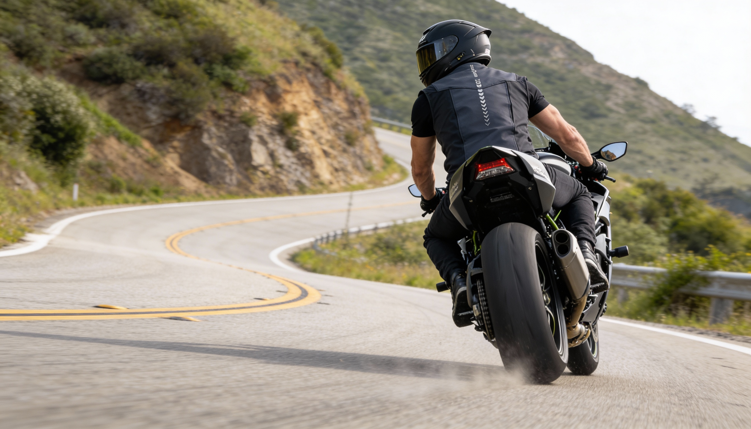 Motorista conduciendo una moto deportiva en carretera de montaña protegido con el chaleco airbag LITE VEST en color negro.