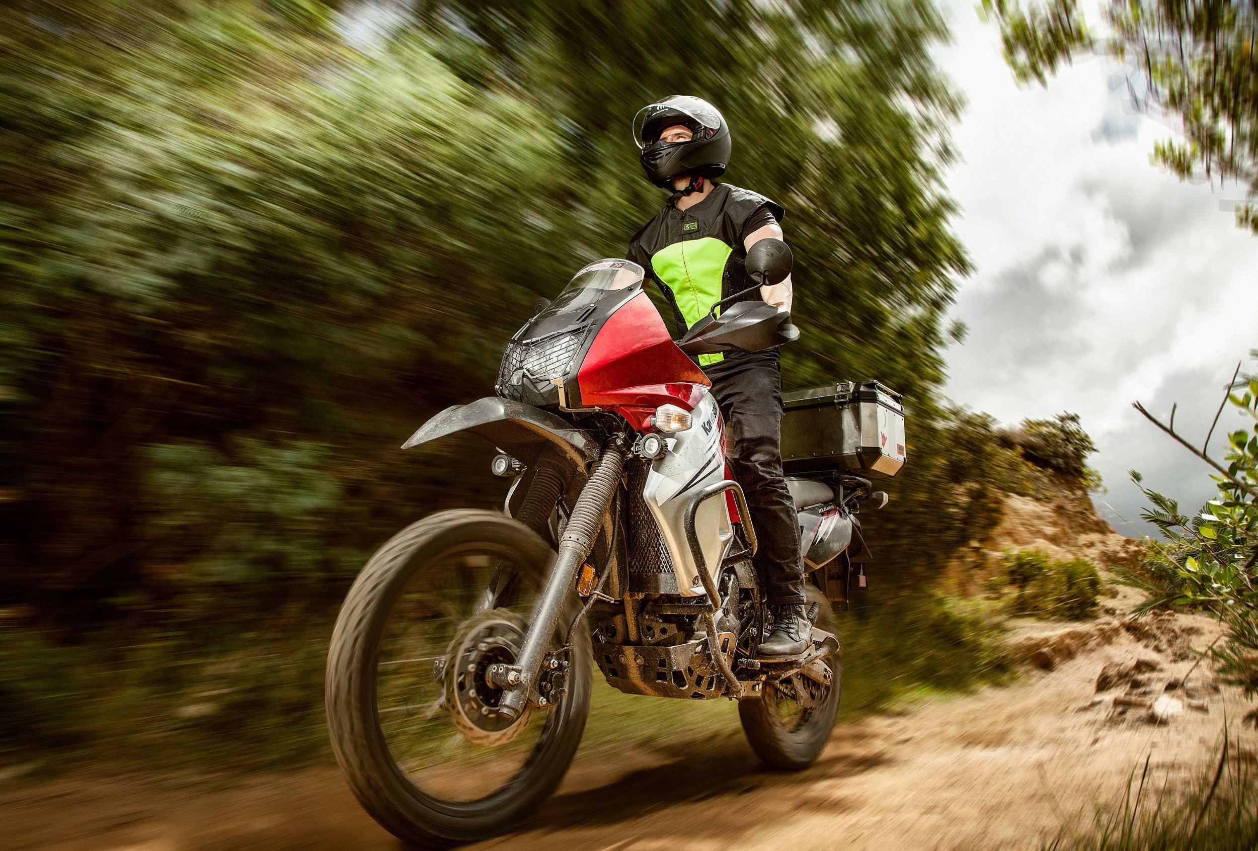 Motorista conduciendo una moto trail de aventura en camino de tierra protegido con el chaleco airbag CHOPPER VEST amarillo