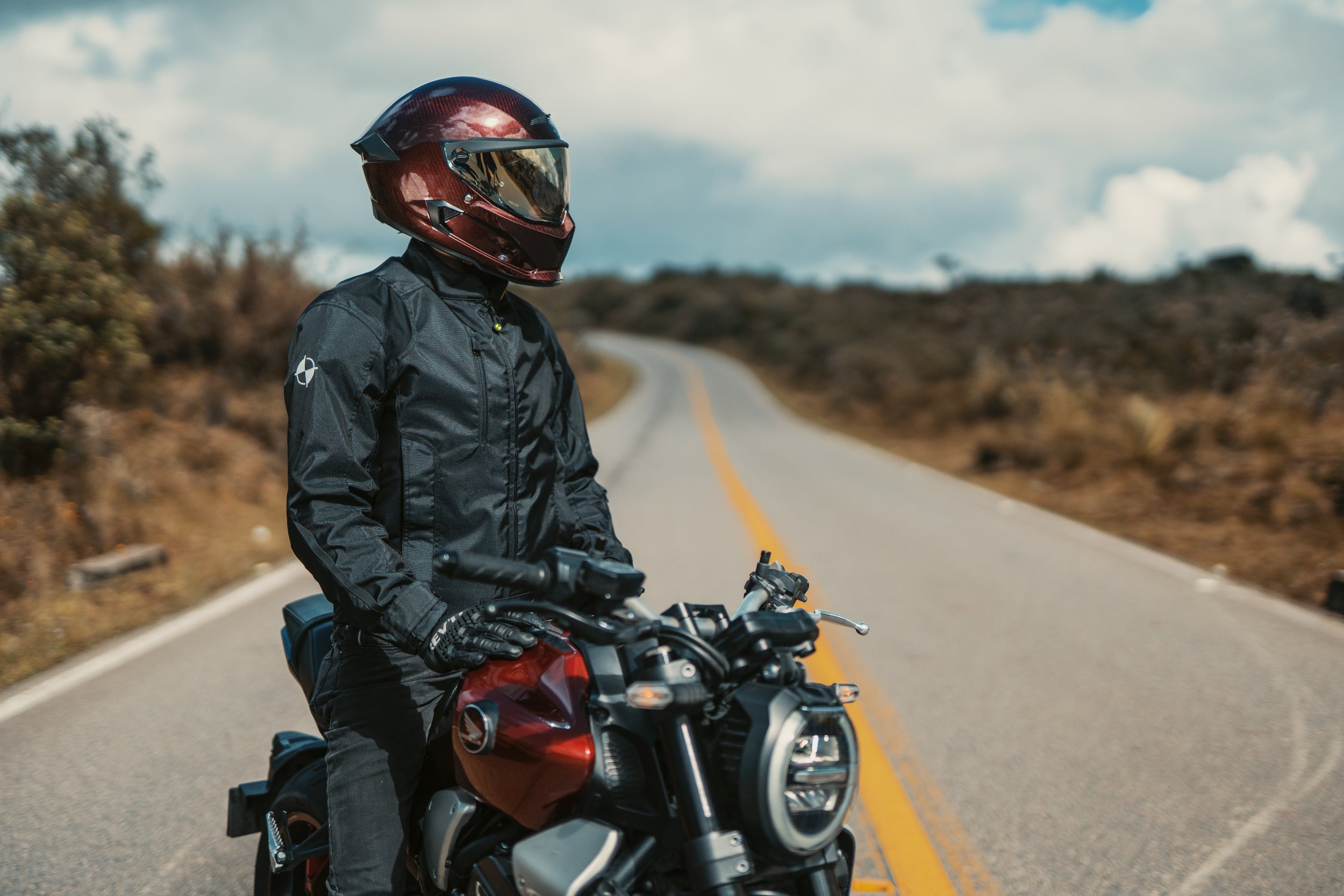 Motorista conduciendo una moto tipo naked en carretera, protegido con la chaqueta con airbag negra URBAN JACKET.