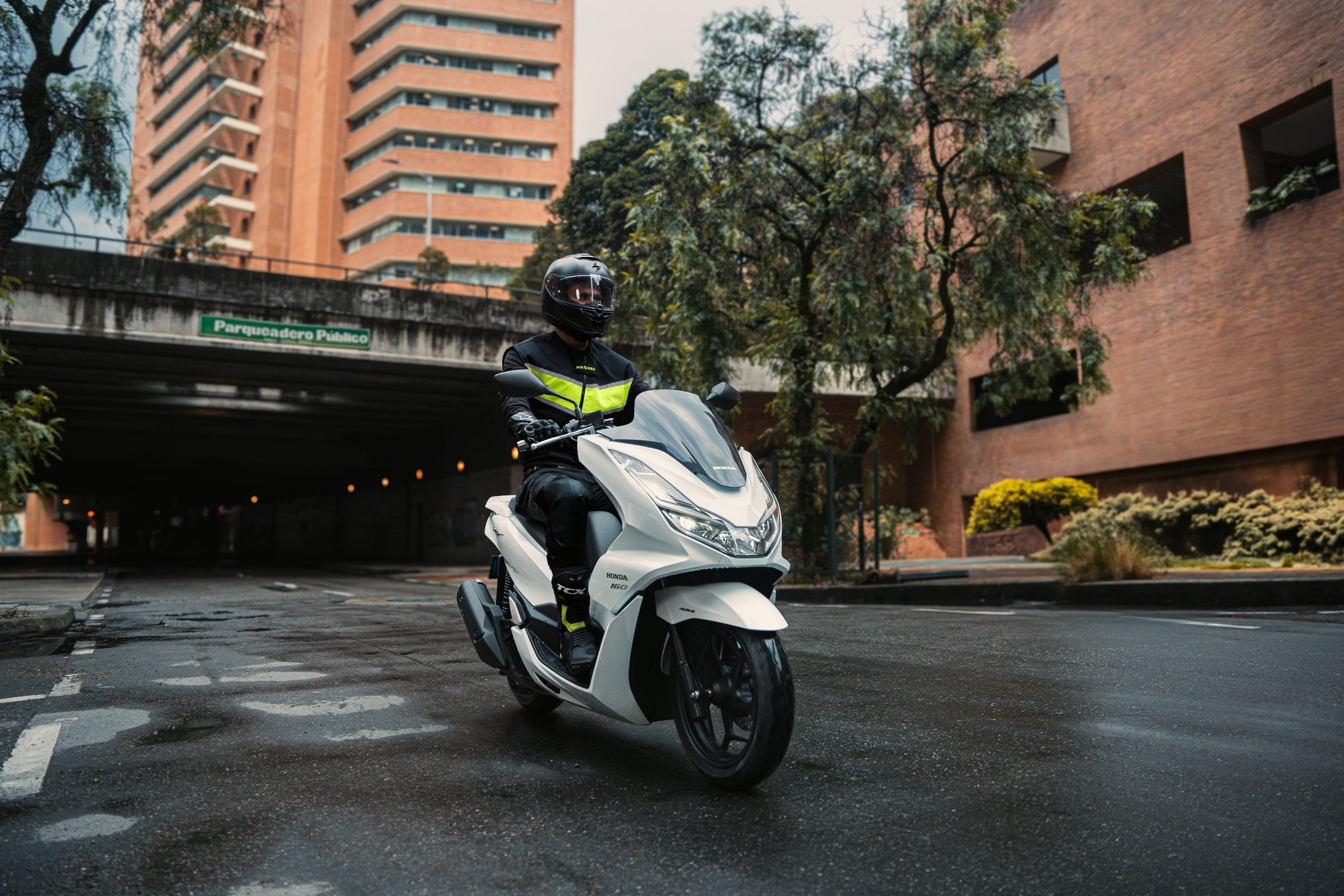 Motorista conduciendo un scooter en la ciudad equipado con el chaleco airbag de alta visibilidad WISE VEST de Airobag